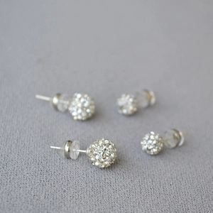 Macro shot of 925 silver stud earrings with glittering white crystal clay balls in two sizes