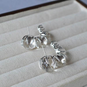Macro shot of three clear glass beads on a C-shaped silver earring in a jewelry box