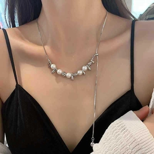 Dettaglio della collana a catena serpente d'argento con perle bianche e ciondoli in metallo