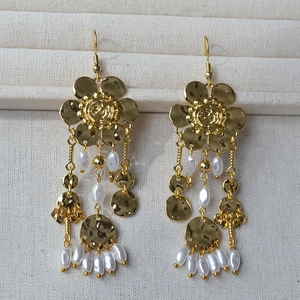 Vintage golden flower tassel earrings with white pearls on a soft jewelry display tray