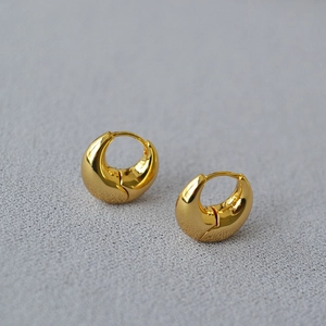 Detailed macro view of gold-plated crescent hoop earrings with a high-polished finish