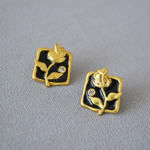 Detail of vintage square stud earrings with gold rose relief on black enamel base