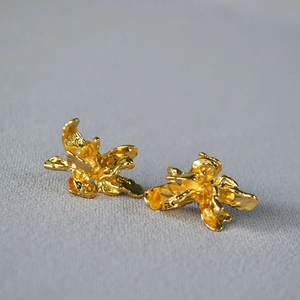 Détail macro de boucles d'oreilles fleurs dorées irrégulières à texture organique
