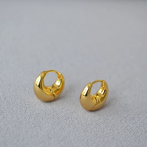 Macro view of polished gold teardrop hoop earrings with elegant mirror finish and round lines