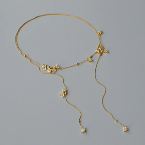 Dettaglio della collana lariat dorata con delicati fiori di cristallo bianco su catena lunga