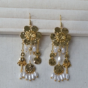 Detail of gold flower petal earrings with hanging pearls and textured metal tassels