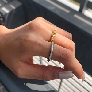 Detail of layered gold pavé ring and silver band worn on fingers for a luxury stackable look