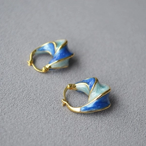 Artistic gold spiral earrings with blue enamel finish in a vintage aesthetic