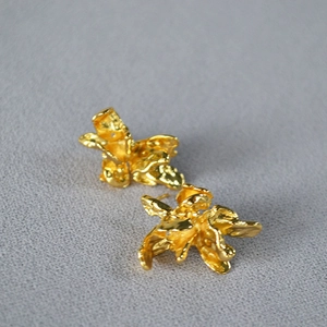 Vue macro de boucles d'oreilles dorées irrégulières avec texture de lave sur la surface