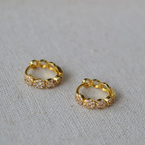 French style gold plated hoop earrings with zircon flowers on a textured fabric