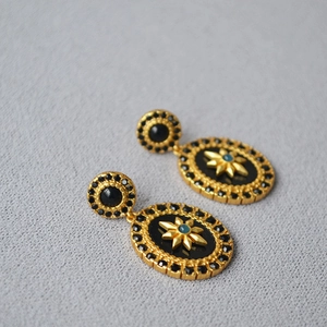 Detail of vintage gold earrings with black enamel, star motif and turquoise bead