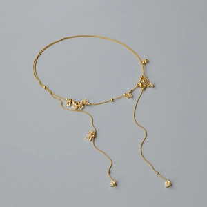 Dettaglio di collana dorata a strati con ciondoli floreali in cristallo e zirconi