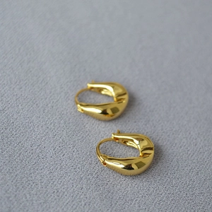 Detailed view of polished gold teardrop earrings with a glossy metallic finish