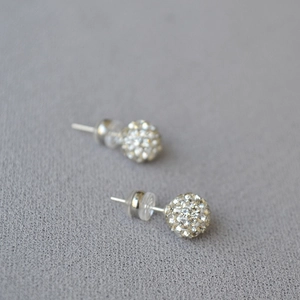 Macro detail of 925 silver stud earrings with sparkling pavé crystals on grey fabric