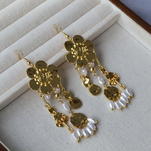 Detail of gold floral tassel earrings with white pearls and brushed metal discs