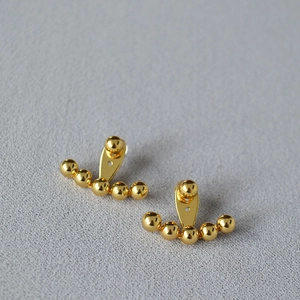 Detalle macro de los aretes de latón chapados en oro con aguja de plata 925