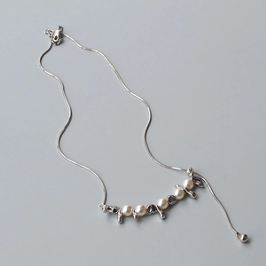 Dettaglio della collana a catena serpente regolabile con perle bianche e ciondoli lava