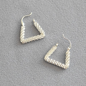 Detailed view of silver triangular earrings featuring unique spiral textured metal surfaces