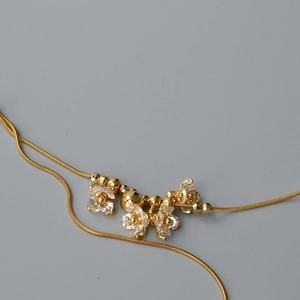 Dettaglio della collana dorata a doppio strato con fiori e cristalli di zircone