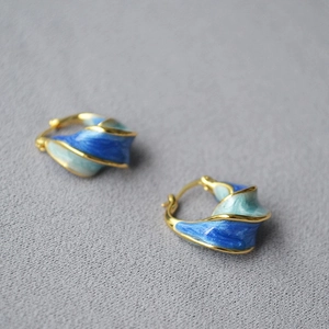 Detail of spiral earrings with blue and green enamel gradient on gold metal base