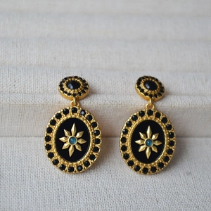 Detail of vintage gold earrings with black oval center and blue starburst gem