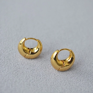 Detailed view of chunky C-shape gold plated brass huggie hoop earrings with high polish