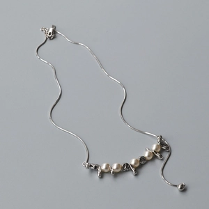 Dettaglio della collana a catena serpente argento con perle bianche e elementi in metallo