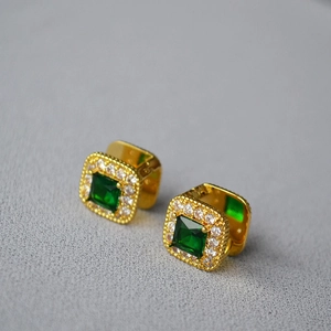 Close-up of vintage gold-plated earrings featuring emerald-cut stones and zircon halo
