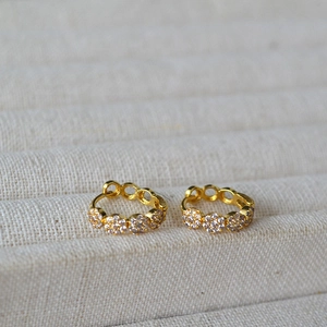 Close-up of golden zircon hollow hoop earrings featuring intricate small flower motifs
