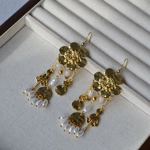Detail of gold flower earrings with long fringe chains and teardrop white pearls