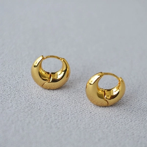 Macro shot of chunky gold plated hoop earrings with a polished mirror finish detail