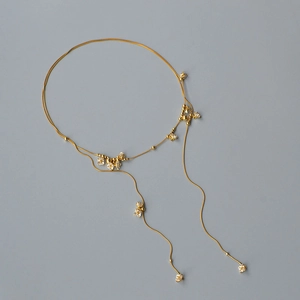 Dettaglio della collana a doppio strato dorata con delicati ciondoli a fiore di cristallo