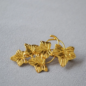 Macro shot of gold vine leaf brooch featuring detailed metallic texture and leaf layers