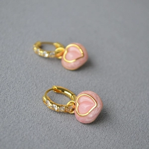 Gros plan de boucles d'oreilles cœur pêche avec zircons brillants et plaqué or