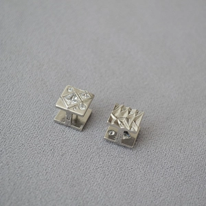 Detailed macro of silver cufflinks featuring crystal zircon inlays and hammered metal texture