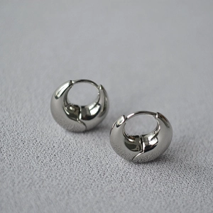Detailed view of polished silver crescent moon earrings on a textured gray background