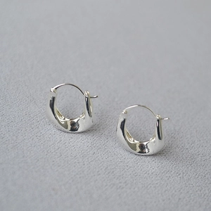 Macro shot of silver irregular U-shaped earrings with molten lava texture and minimal design