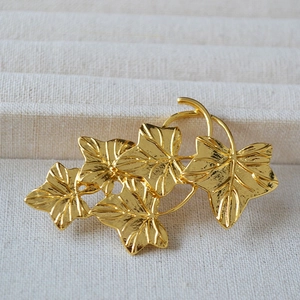 Detailed view of matte gold vine leaf brooch featuring intricate veins on wool fabric