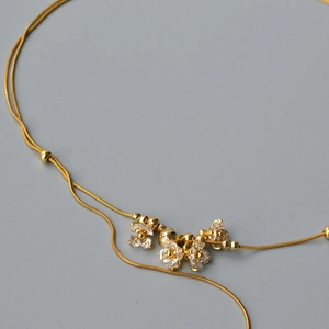 Dettaglio collana a catena serpente dorata con fiori in zircone e perline di metallo