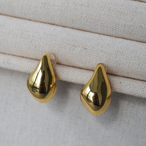 Detail of gold teardrop earrings with a polished finish on a jewelry display tray