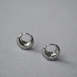 Macro shot of chunky silver hoop earrings with polished mirror finish and snap closure