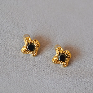 Detail view of gold-plated brass floral earrings with center black faceted gemstone
