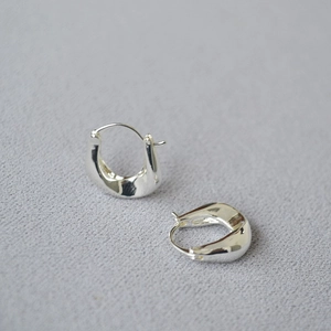 French minimalist silver irregular U-shaped hoop earrings on grey textured fabric