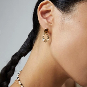 Gros plan de boucles d'oreilles vintage en laiton avec œil de tigre et petite perle