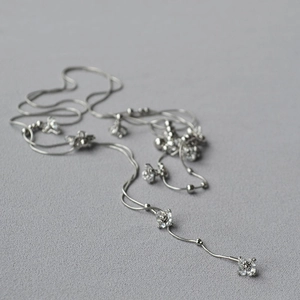Dettaglio macro della collana a catena serpente argento con ciondoli a fiori in zircone