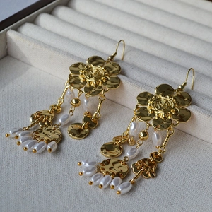 Detailed close-up of gold flower earrings with white pearl tassels and hammered finish