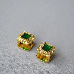 Detail view of gold-plated brass earrings with emerald square stone and cubic zirconia