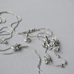 Macro di una catena snake d'argento a due strati con fiori di cristallo e perle in metallo