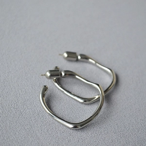 Close-up of silver irregular liquid metal hoop earrings with high polish finish