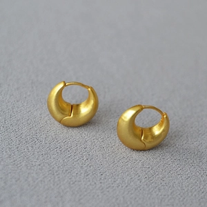 Detailed close-up of chunky matte gold hoops with crescent design and secure clasp